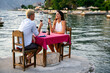 © NDABCREATIVITY - Couple in love drinking wine on romantic dinner at sunset on the beach.