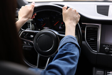 Wall Mural - Woman holding steering wheel while driving her car, closeup