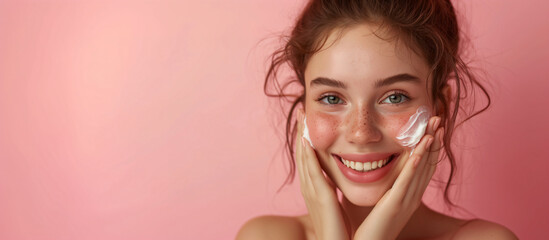 Wall Mural - Happy smiling young woman with perfect skin puts a moisturizing cream on her face. Girl using skincare product on facial skin. Natural beauty and cosmetic concept. Banner with copy space