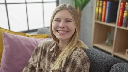 Canvas Print - Home shenanigans, hilarious young woman with puffed cheeks making a funny face while sitting on the living room sofa, a crazy expression on her blonde, frowning face