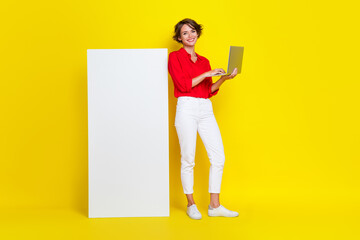 Full length portrait of attractive cheerful person hold use wireless netbook isolated on yellow color background