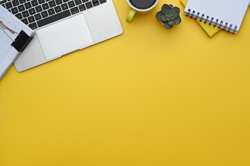 Wall Mural - Top view of laptop, notepad, coffee cup and financial documents on yellow background