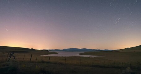 Poster - night sky timelapse in rural area andalusia with lake and mountains as background. foreground of gra