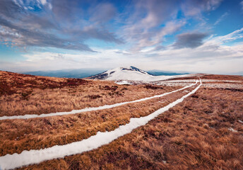 Wall Mural - Melting snow at April in mountains. Amazing spring view of Borzhava mountain range with old country road. Amazing morning scene of Carpathian moiuntains. Beauty of nature concept background.