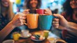 © Tonton1541 - Group of friends toasting with colorful coffee mugs in a cozy cafe, celebrating and enjoying their time together