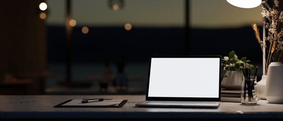 Wall Mural - A modern dark office at night featuring a white-screen laptop computer mockup on a table.