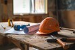 © Fitry - A safety helmet and rolled-up blueprints on a wooden table with construction tools scattered around