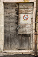 Wall Mural - An aged wooden door, crafted from recycled boards, stands weathered and worn with rusty gutter tube and a no parking sign