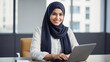 © NONTANUN - Muslim woman wearing hijab, happy smiling face sitting working with laptop in modern office