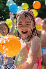 A young girl smiles brightly as she holds a water balloon in her hand, surrounded by a spray of water