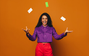 Happy woman using credit cards on orange background.