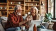 © arhendrix - Happy senior couple using a laptop at home, sharing a moment of laughter and conversation in a cozy living room.