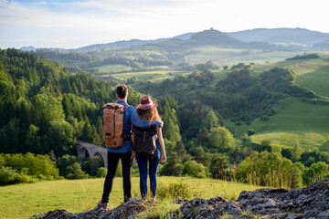 Wall Mural - travellers couple hiking on easy trail in nature with backpacks. young tourist resting, enjoying bre