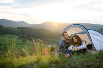 Wall Mural - travellers couple spending time outdoor, sleeping in tent shelter. young tourist sitting in nature, 