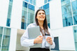© Dusan - One young successful business woman going to work at business office modern building while holding coffee and laptop