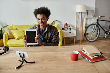 Wall Mural - Young man, African American, holding tablet, in front of yellow table.