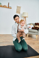 Wall Mural - A young mother sits on a yoga mat, peacefully holding her baby while receiving guidance from her coach during a parents course.