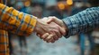 © admin_design - Close-up of two people shaking hands, showcasing partnership, agreement, and teamwork concepts. Blurred background. Outdoor setting.