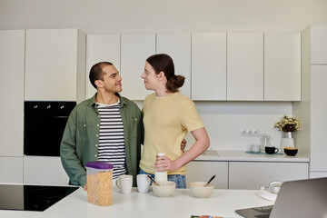 A young gay couple in casual attire share a loving moment in their modern kitchen.