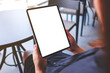 © Farknot Architect - Mockup image of a woman holding digital tablet with blank white desktop screen in cafe