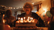 © chekart - A happy elderly woman with glasses makes a wish in front of a large sweet cake with lots of candles. The pensioner celebrates the anniversary with friends. She smiles and laughs