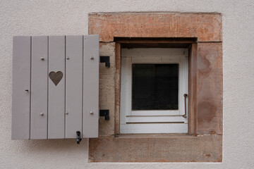 View of a graphical colorful Alsacian window with an open wooden shutter in a street of Goxwiller.