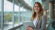 © yj - A smiling young business woman holding a tablet in a modern office. generative AI