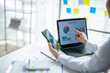 © Wasana - A woman is using a laptop and a cell phone to look at graphs and charts