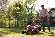© New Africa - Man cutting green grass with lawn mower in garden