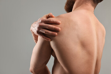 Wall Mural - Man touching his shoulder on light grey background, closeup