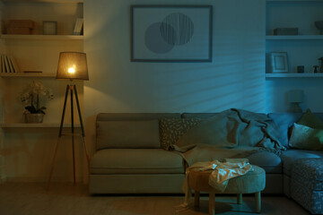 Wall Mural - Stylish room interior with couch and lamp at night