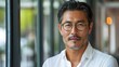 © Антон Сальников - Stylish 45-year-old Korean gentleman wearing glasses, formal slick hairstyle, smooth beardless face in a modern office building, wearing white shirt, beside a huge window