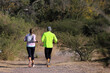 © Acento Creativo - Couple running in mountain area. Runners exercising in native bush. Athletes running. Adult man and woman exercising outdoors.