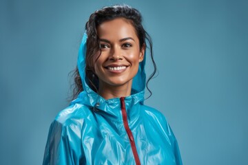 Wall Mural - Portrait of a glad indian woman in her 30s sporting a waterproof rain jacket in front of soft blue background