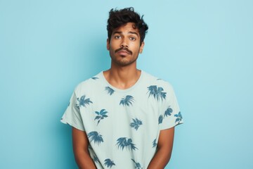 Wall Mural - Portrait of a glad indian man in his 20s donning a trendy cropped top while standing against soft blue background