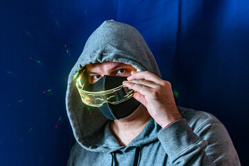 A guy in a white mask with a red valve with futuristic beige glasses in his hands, close-up