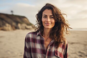Wall Mural - Portrait of a satisfied woman in her 20s dressed in a relaxed flannel shirt in sandy beach background