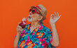 © oneinchpunch - Grandfather portraits on colored backgrounds. Old man with hawaiian shirt celebrating on vacation, and drinking  tropical cocktails.