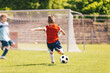 © matimix - Little Boy Kick Soccer Ball During League Match. Happy Kid Have Fun Shooting Ball Towards Soccer Goal. School Soccer Tournament Game For Kids