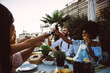© oneinchpunch - Group of friends having fun on the rooftop of a beautiful rooftop. Young people celebrating on a modern terrace with the view at the aperitif time.