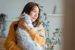 © oatawa - Young asian woman hugging cute grey persian cat on couch in living room at home, Adorable domestic pet concept.