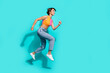 © deagreez - Full length photo of hurrying excited woman wear pink orange top jumping high running fast empty space isolated teal color background
