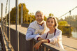 © Studio Romantic - Portrait of a happy senior couple looking at camera during walking in a city park at sunset, enjoying a holiday date. Smiles and joy of spending special moment together and happy retirement.