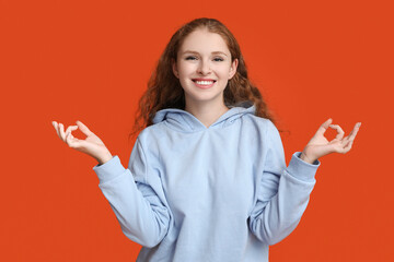 Wall Mural - Portrait of relaxed young woman meditating on red background