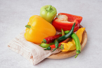 Poster - Wooden plate with different fresh peppers on white background