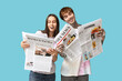 © Pixel-Shot - Young couple with newspapers on blue background