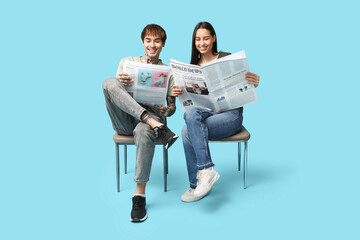 Canvas Print - Young couple with newspapers on blue background