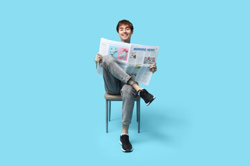 Canvas Print - Handsome young man with newspaper on blue background