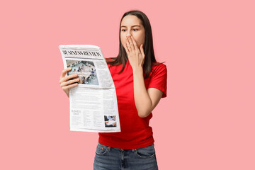 Poster - Shocked young woman with newspaper on pink background