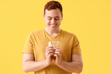 Poster - Young happy man smiling and holding doner kebab on yellow background